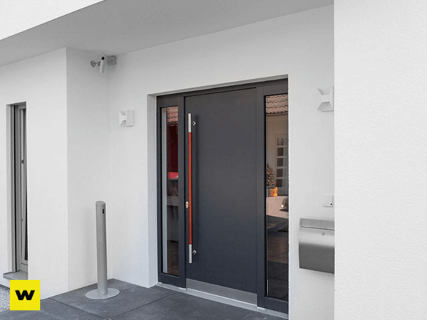 Moderne Haustür aus Aluminium mit Seitenteil und Edelstahlgriff an weißer Fassade.